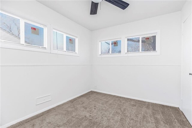 carpeted spare room featuring ceiling fan