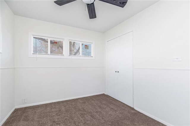 unfurnished bedroom featuring dark colored carpet, ceiling fan, and a closet