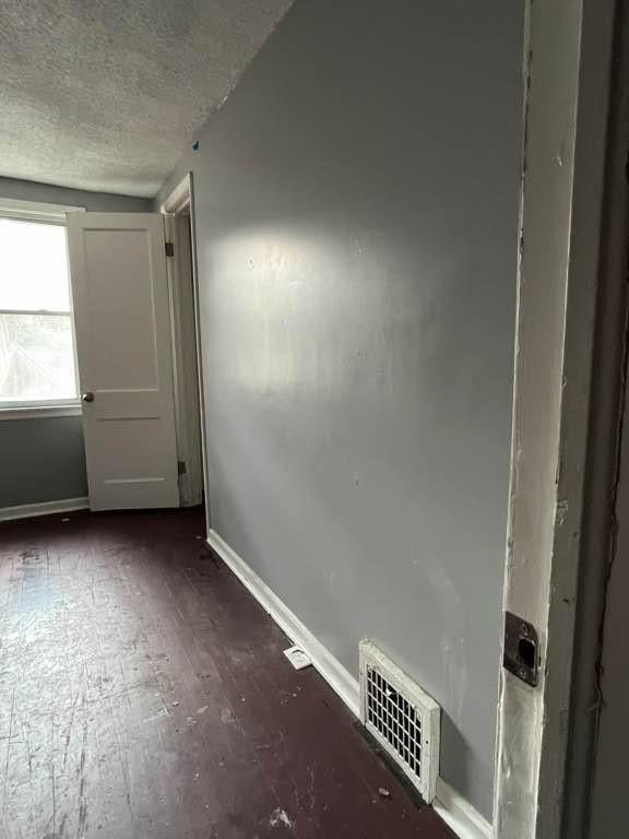 empty room featuring a textured ceiling and dark hardwood / wood-style flooring