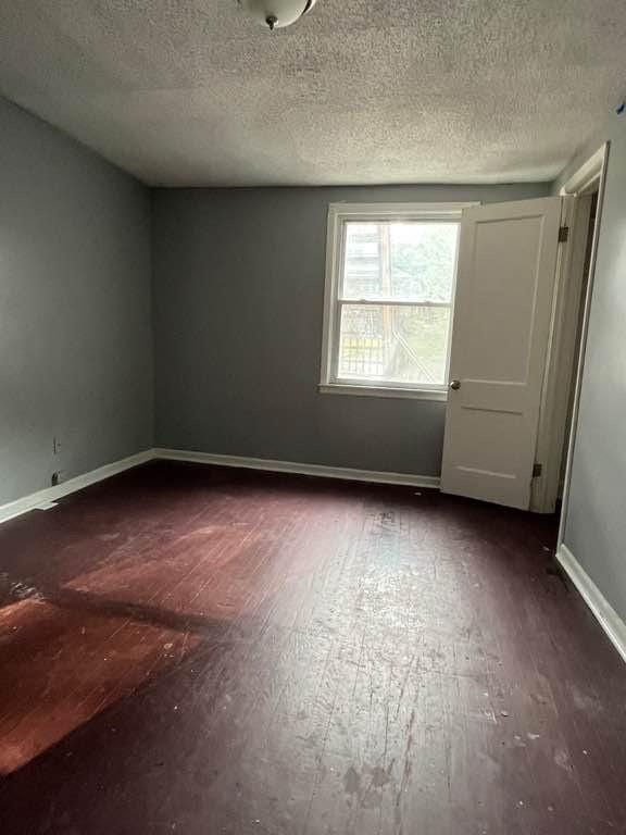 spare room with dark hardwood / wood-style floors and a textured ceiling