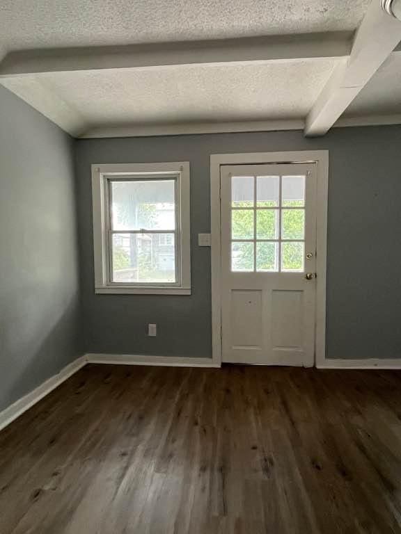 doorway to outside with a textured ceiling, dark hardwood / wood-style flooring, and beam ceiling