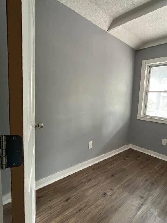 spare room with a textured ceiling and dark wood-type flooring