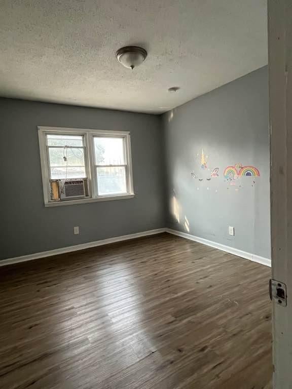 unfurnished room with a textured ceiling, dark hardwood / wood-style floors, and cooling unit