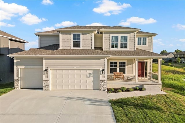 prairie-style home with covered porch, stone siding, an attached garage, and driveway