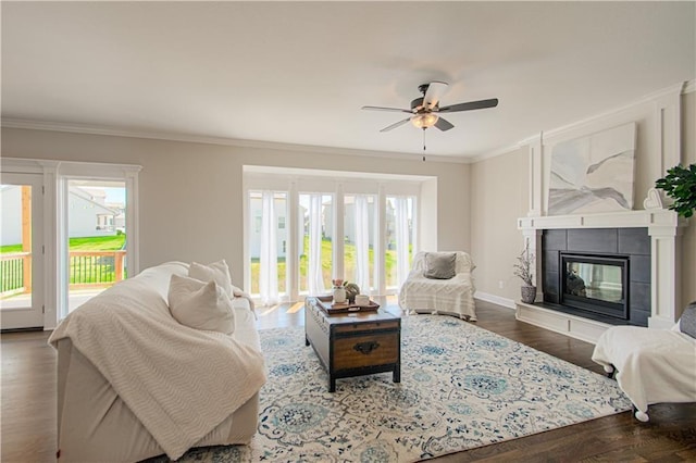 living area featuring a healthy amount of sunlight, wood finished floors, crown molding, and a tile fireplace