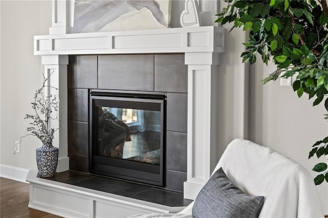 room details with a tiled fireplace and hardwood / wood-style flooring