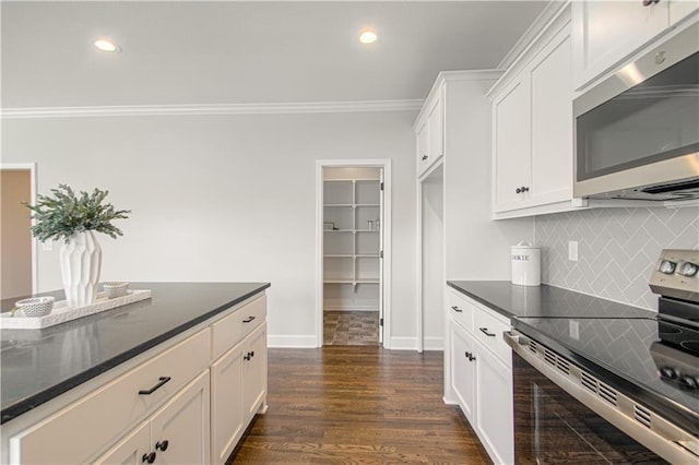 kitchen featuring crown molding, backsplash, appliances with stainless steel finishes, white cabinets, and dark wood-type flooring