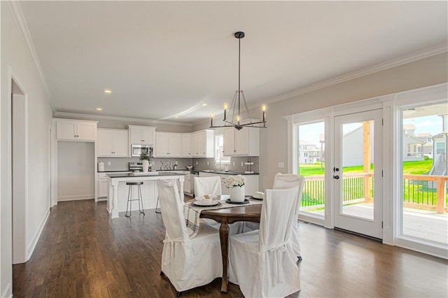 dining room featuring dark wood-type flooring, a wealth of natural light, an inviting chandelier, and crown molding