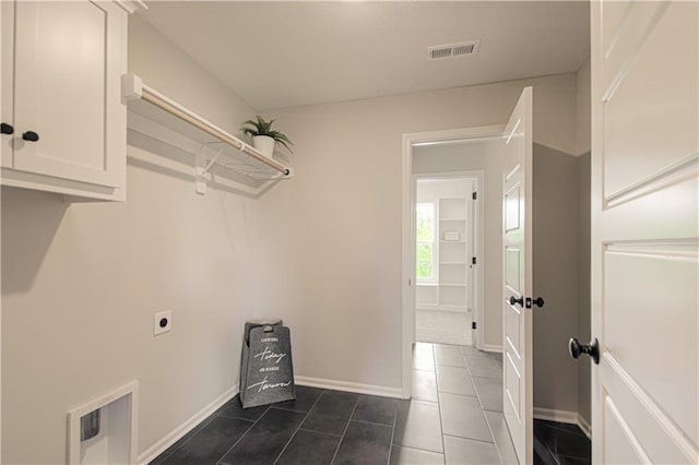 laundry room featuring dark tile patterned flooring, electric dryer hookup, and cabinets