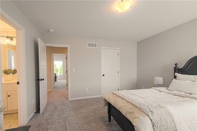 bedroom featuring light colored carpet, ensuite bath, and a closet