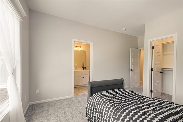 bedroom with ensuite bathroom, light carpet, a walk in closet, and a closet