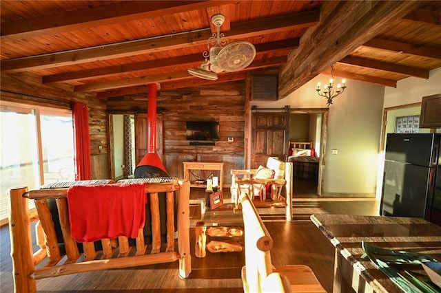 dining space featuring beam ceiling, a barn door, a chandelier, and hardwood / wood-style flooring