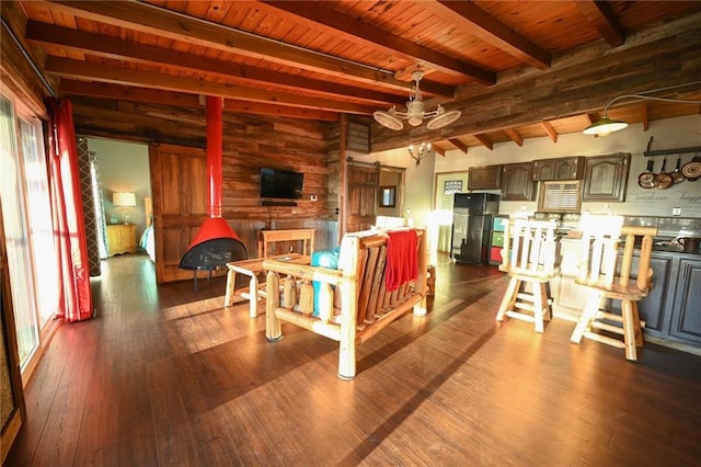 interior space featuring a wood stove, dark wood-type flooring, wooden walls, beam ceiling, and wood ceiling