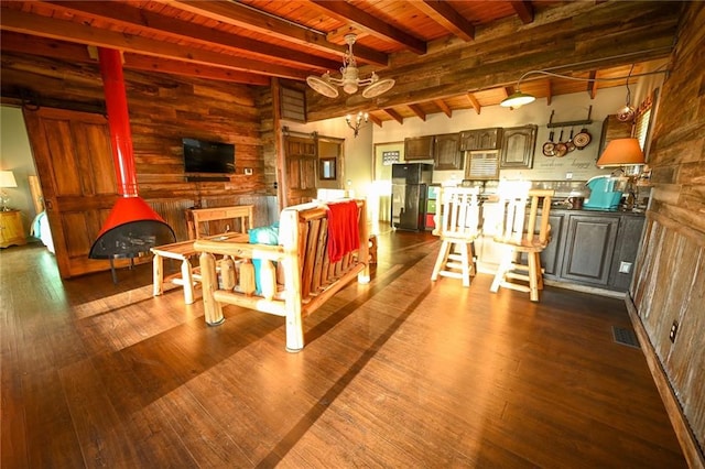 living room featuring wood walls, a wood stove, dark wood-type flooring, beamed ceiling, and wood ceiling