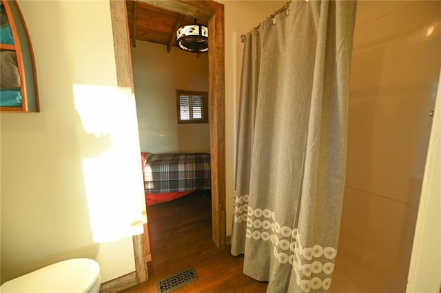 bathroom featuring hardwood / wood-style floors, curtained shower, and toilet