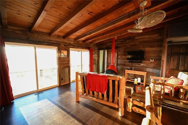 living room featuring beam ceiling, dark hardwood / wood-style flooring, wooden ceiling, and wooden walls