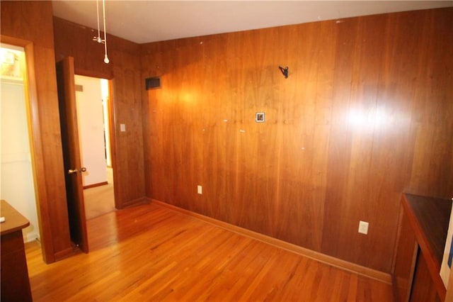 unfurnished bedroom featuring light hardwood / wood-style floors and wooden walls