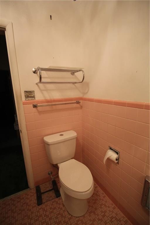 bathroom featuring tile patterned flooring, toilet, and tile walls