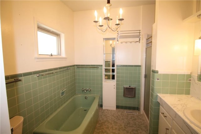 bathroom featuring toilet, tile walls, a chandelier, vanity, and a tub to relax in