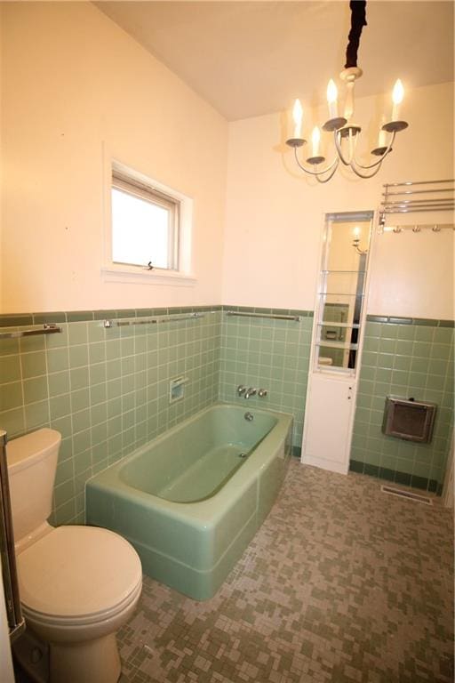 bathroom with tile walls, a bath, tile patterned flooring, toilet, and a chandelier