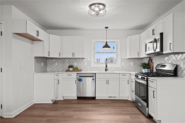 kitchen featuring white cabinets, wood-type flooring, and stainless steel appliances