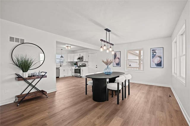 dining space featuring sink, hardwood / wood-style floors, and an inviting chandelier