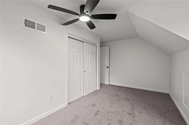 unfurnished bedroom with ceiling fan, a closet, light carpet, and vaulted ceiling