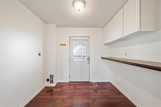 clothes washing area featuring cabinets, a textured ceiling, dark hardwood / wood-style flooring, and electric dryer hookup