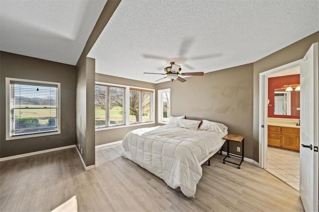 bedroom with ceiling fan, ensuite bath, light hardwood / wood-style flooring, and multiple windows