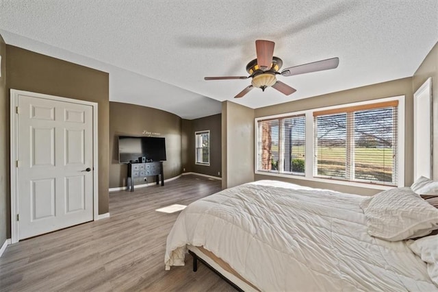 bedroom featuring hardwood / wood-style floors, ceiling fan, and a textured ceiling