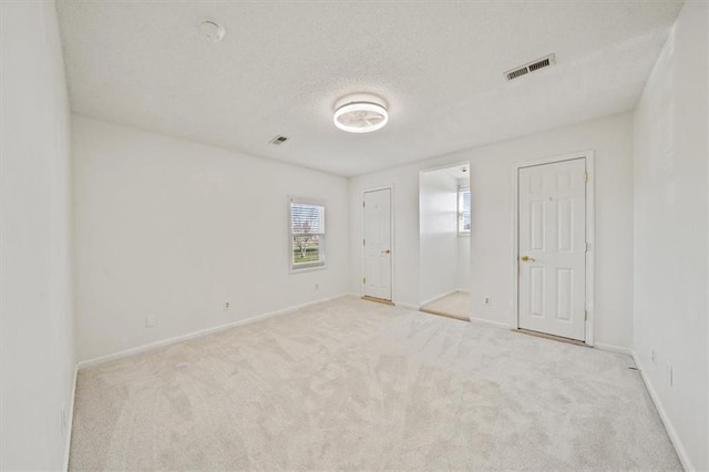 empty room with light carpet and a textured ceiling