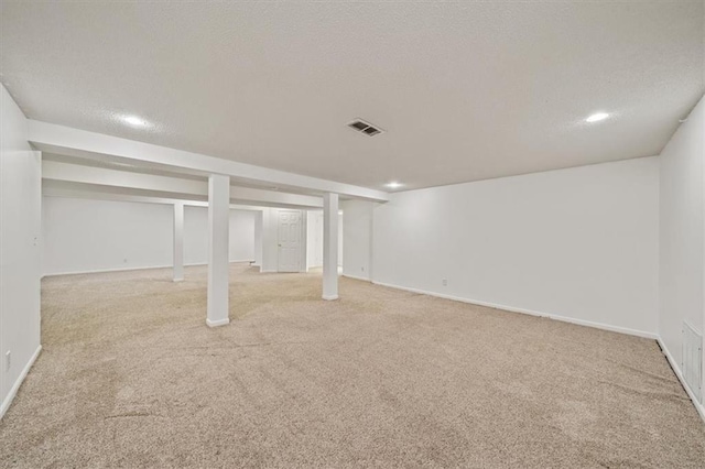 basement featuring a textured ceiling and light colored carpet