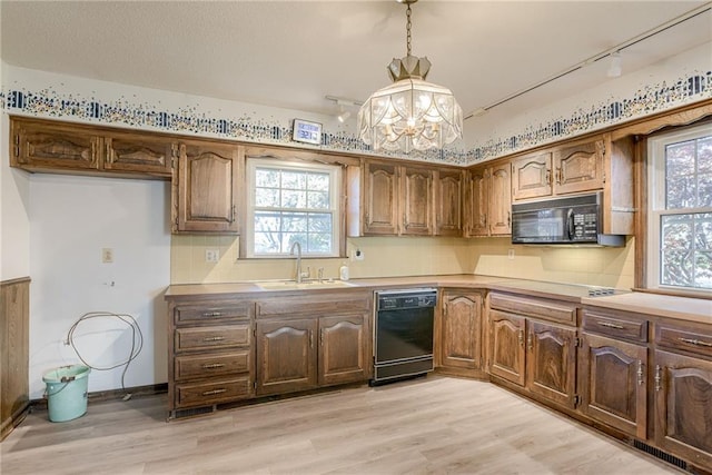 kitchen with pendant lighting, black appliances, plenty of natural light, and sink