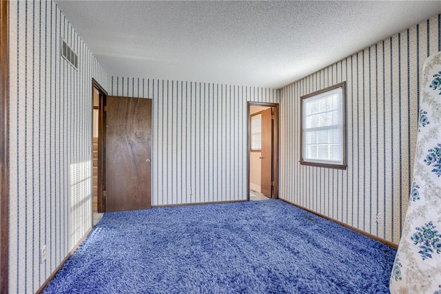 carpeted empty room featuring a textured ceiling