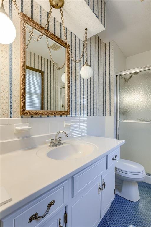 bathroom with tile patterned floors, a shower with door, vanity, and toilet