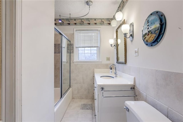 full bathroom with enclosed tub / shower combo, tile patterned floors, a textured ceiling, vanity, and tile walls