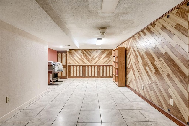 interior space with wooden walls, tile patterned flooring, ceiling fan, and a textured ceiling