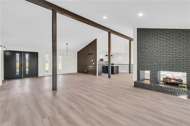 unfurnished living room featuring vaulted ceiling with beams, light wood-type flooring, and a fireplace