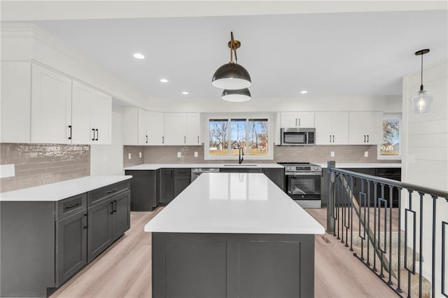 kitchen with decorative light fixtures, white cabinetry, and appliances with stainless steel finishes