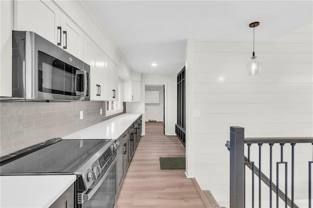 kitchen featuring decorative backsplash, appliances with stainless steel finishes, light wood-type flooring, decorative light fixtures, and white cabinetry