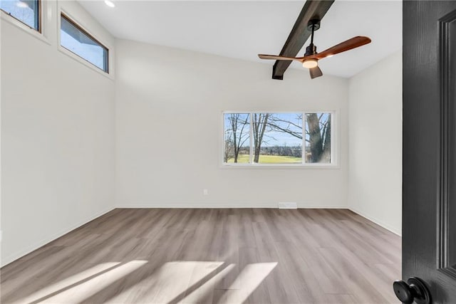 spare room featuring beamed ceiling, light hardwood / wood-style flooring, and ceiling fan