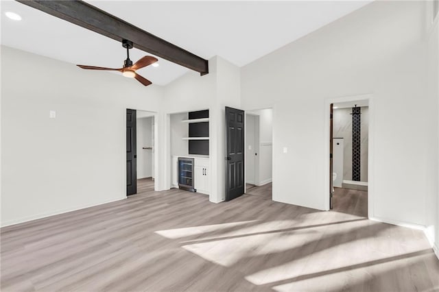 unfurnished bedroom with wine cooler, light hardwood / wood-style flooring, ceiling fan, connected bathroom, and beam ceiling