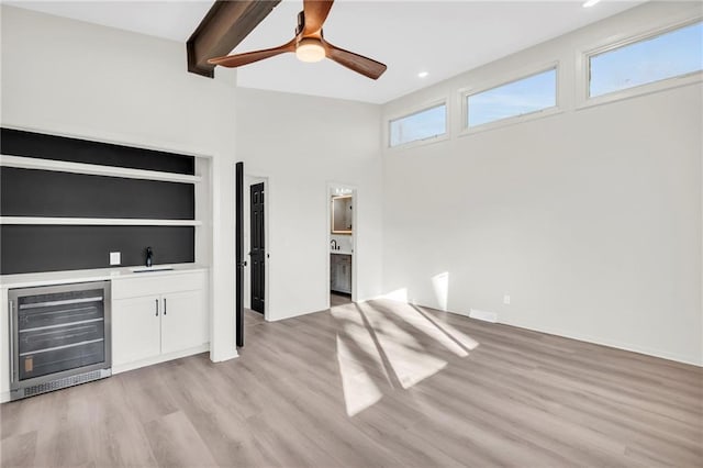 interior space featuring white cabinetry, sink, ceiling fan, wine cooler, and light wood-type flooring