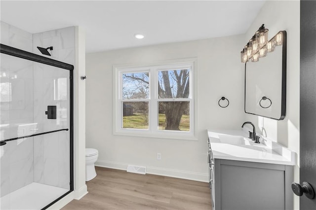 bathroom featuring toilet, vanity, a shower with shower door, and wood-type flooring