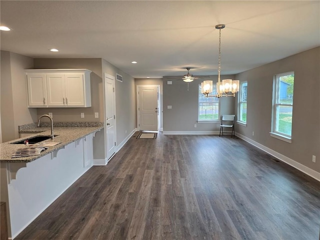 kitchen featuring white cabinets, pendant lighting, sink, a breakfast bar area, and dark wood-type flooring