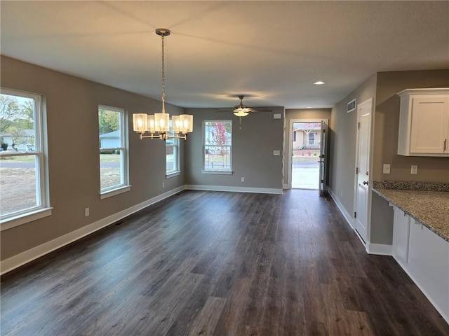 unfurnished dining area with ceiling fan with notable chandelier and dark wood-type flooring