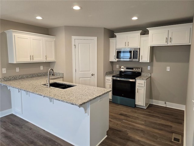 kitchen featuring stainless steel appliances, dark hardwood / wood-style floors, sink, white cabinets, and kitchen peninsula