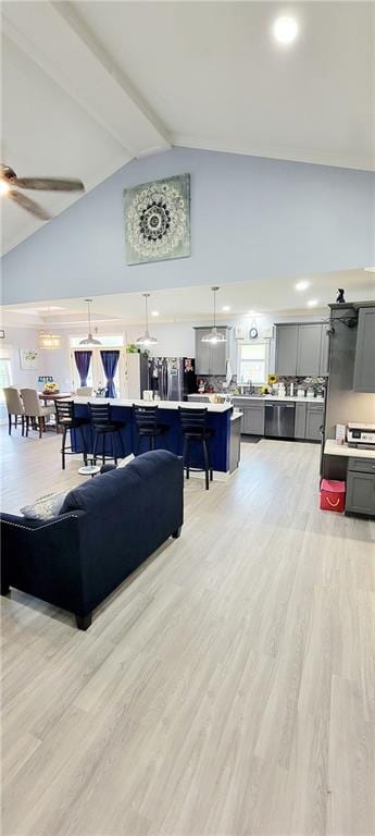 living room featuring high vaulted ceiling, light hardwood / wood-style flooring, and ceiling fan