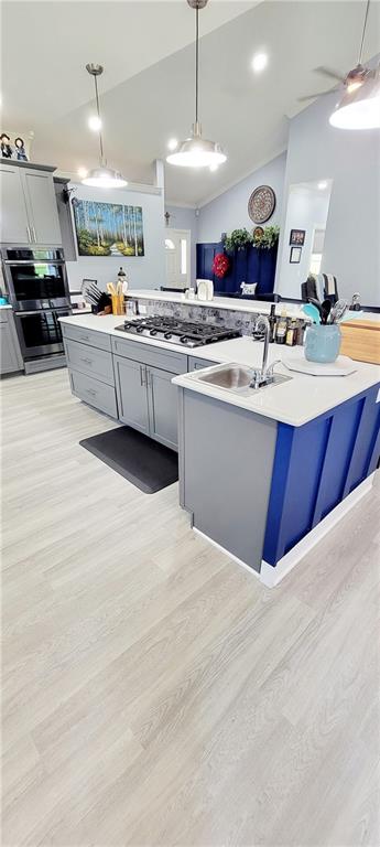 kitchen with gray cabinetry, decorative light fixtures, light hardwood / wood-style floors, and stainless steel appliances