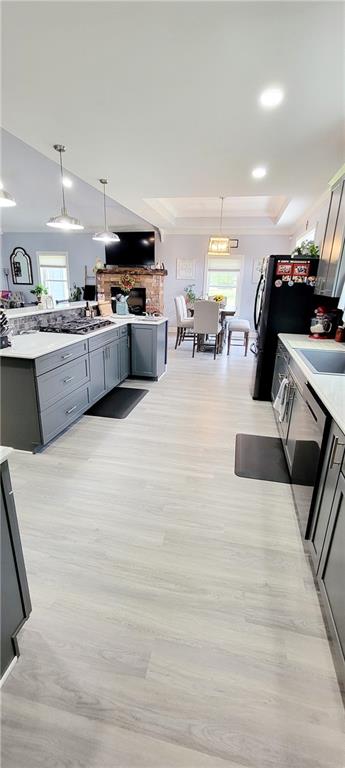 kitchen with gray cabinetry, sink, pendant lighting, and light hardwood / wood-style flooring